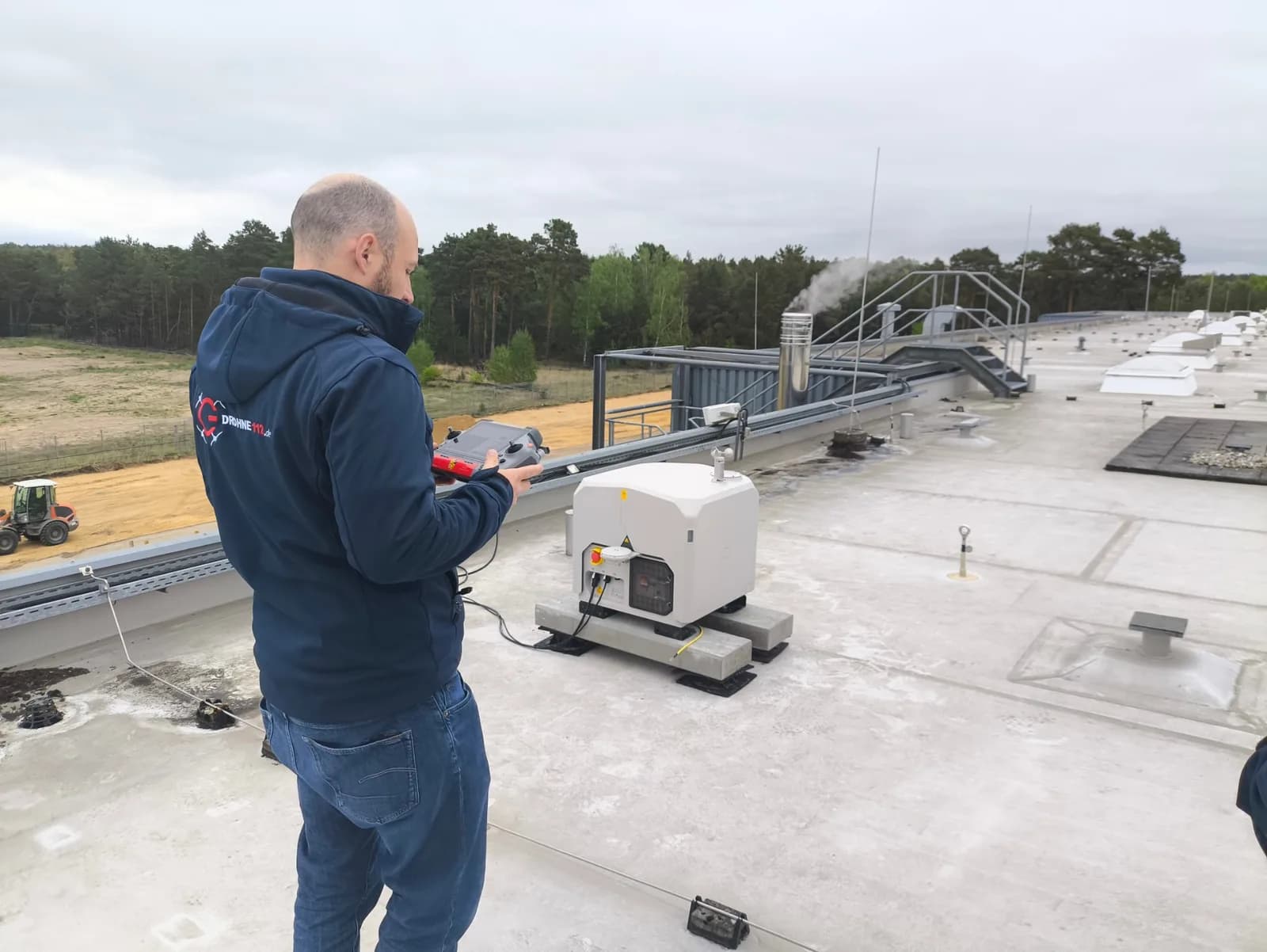 Fernpilot mit Controller neben der geöffneten DJI Dock 3 auf dem Dach